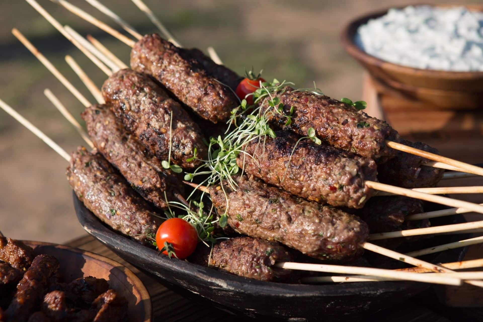 Grilled beef kofta skewers served with microgreens and cherry tomatoes.