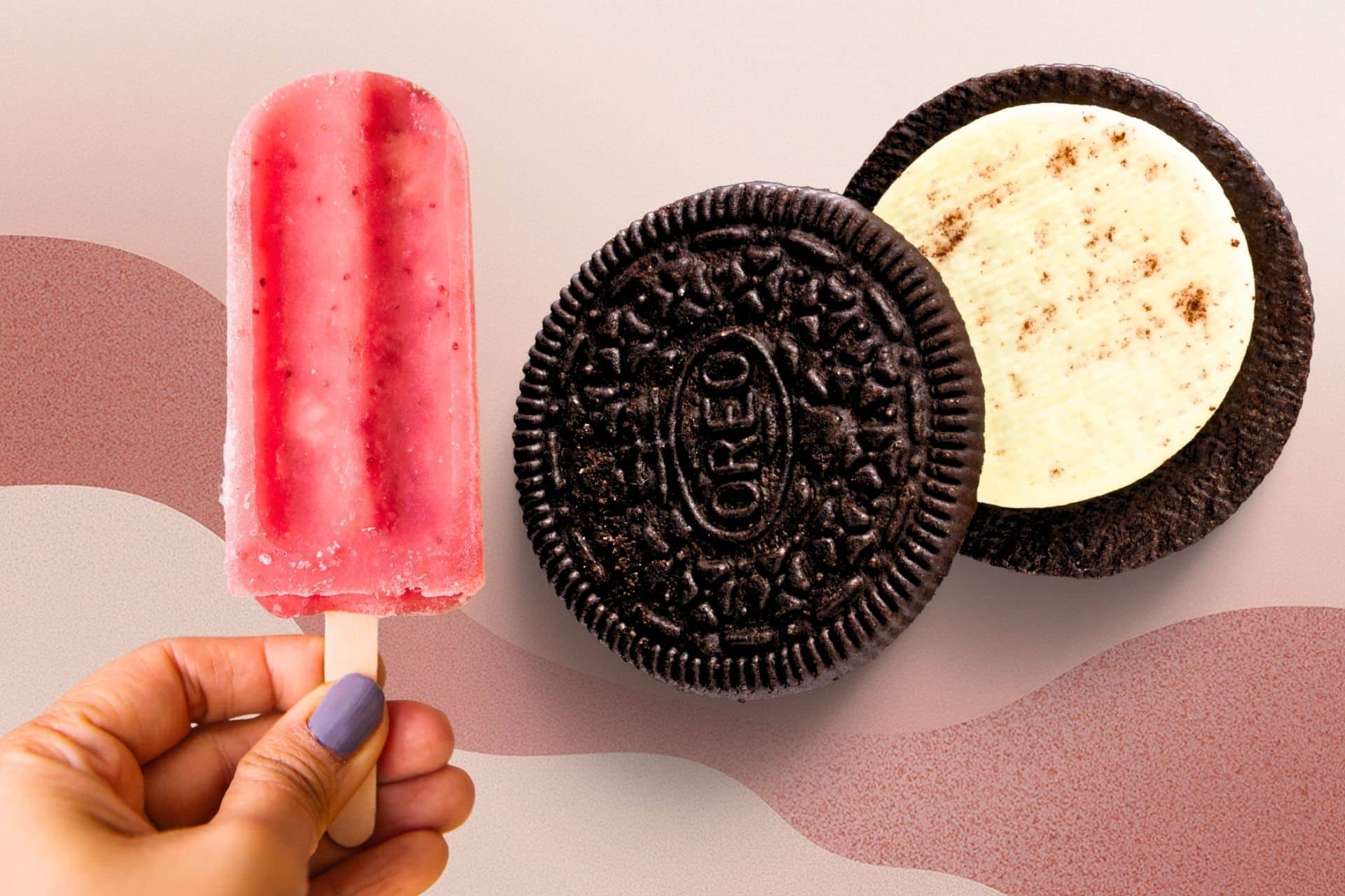 Pink popsicle beside Oreo cookies with vanilla creme filling.