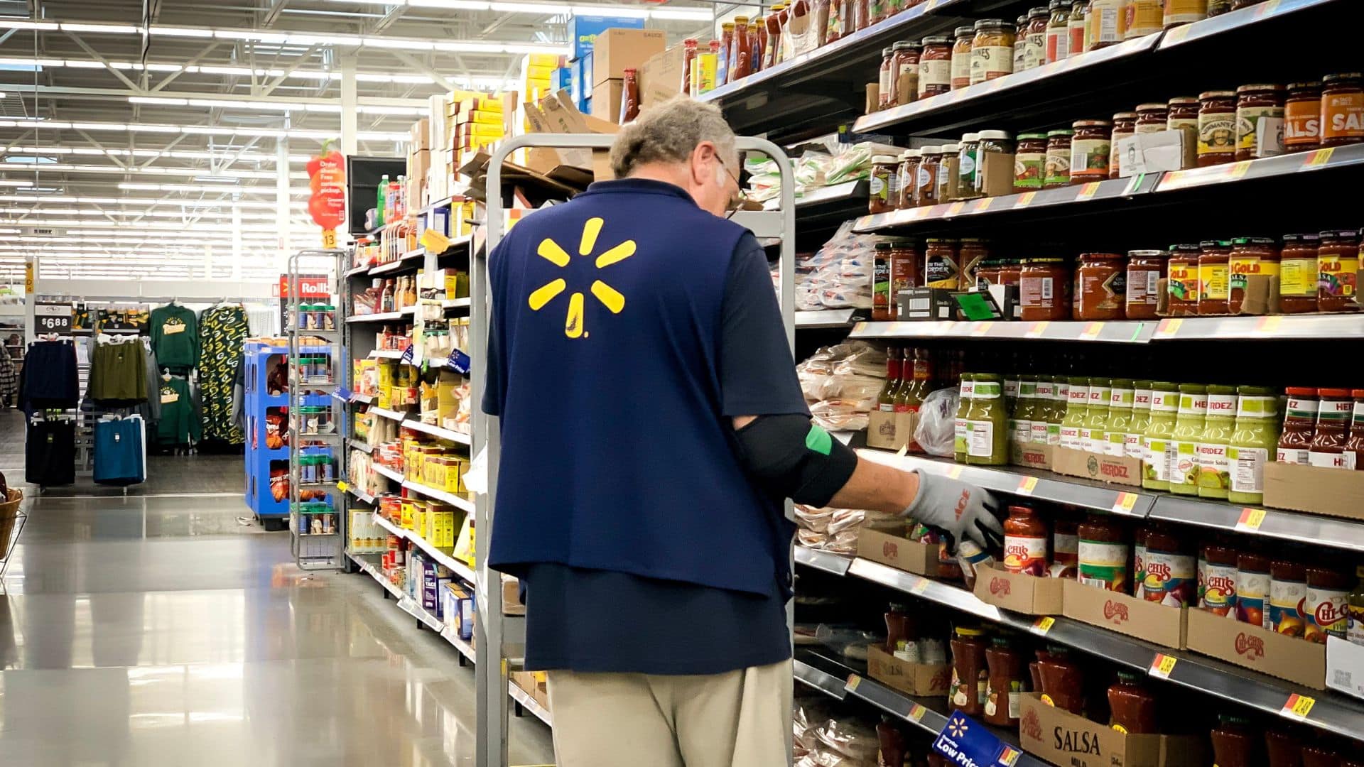Walmart employee stocking shelves in store aisle.