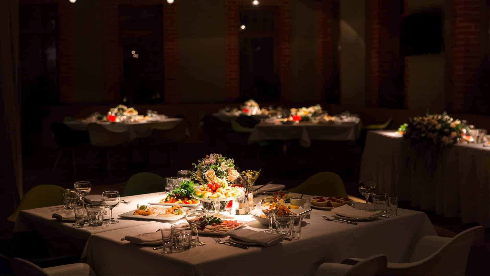 Dimly lit restaurant dining room with set tables and plated food.