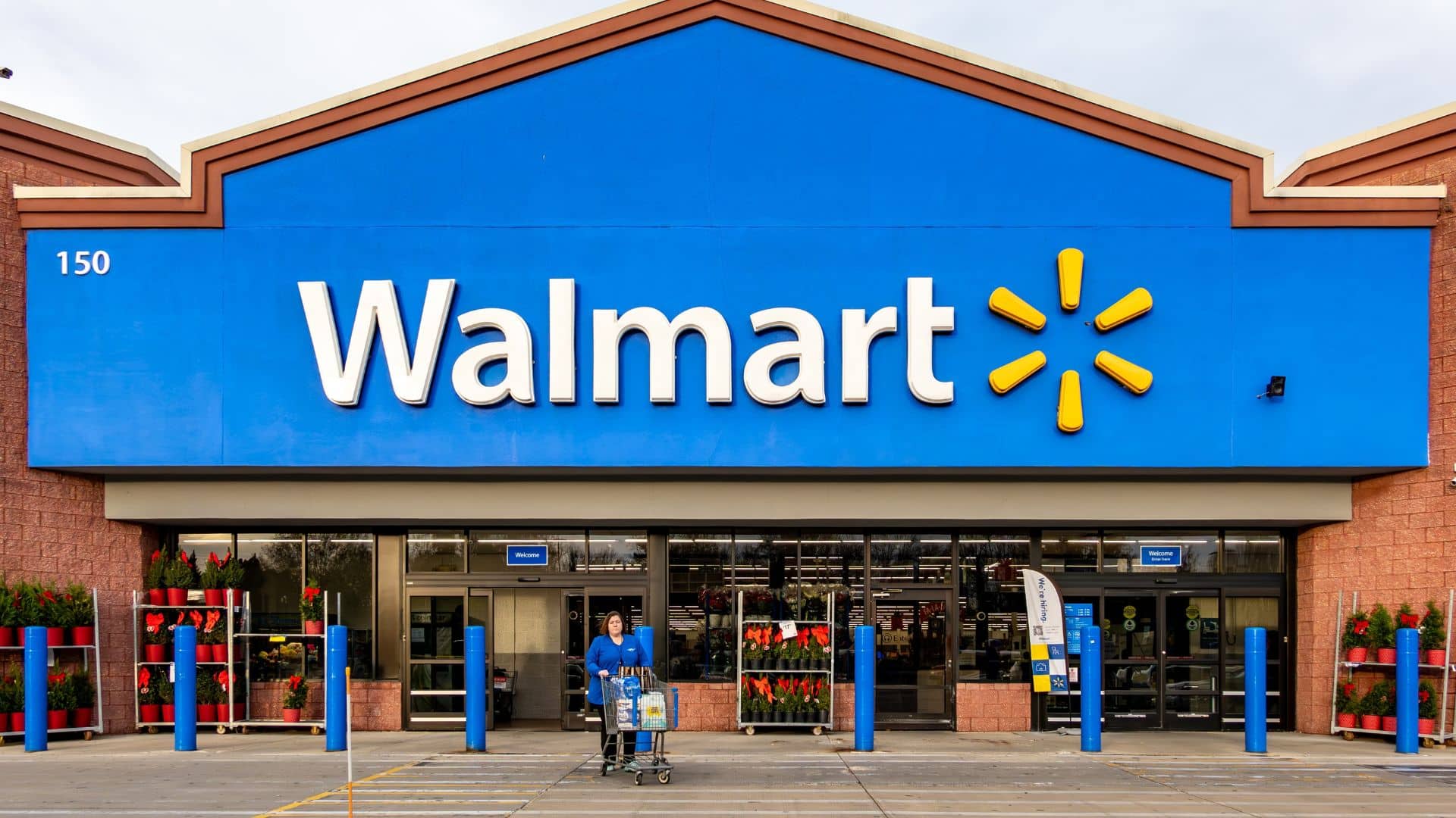 Walmart store exterior with an employee pushing a cart outside the entrance.