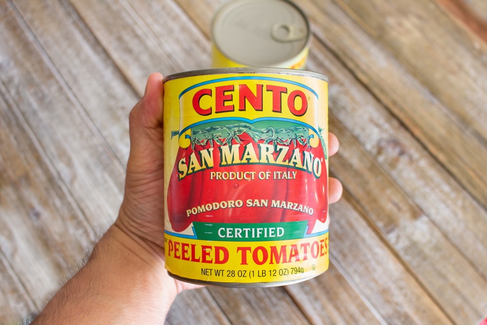 Hand holding a can of Cento San Marzano peeled tomatoes.