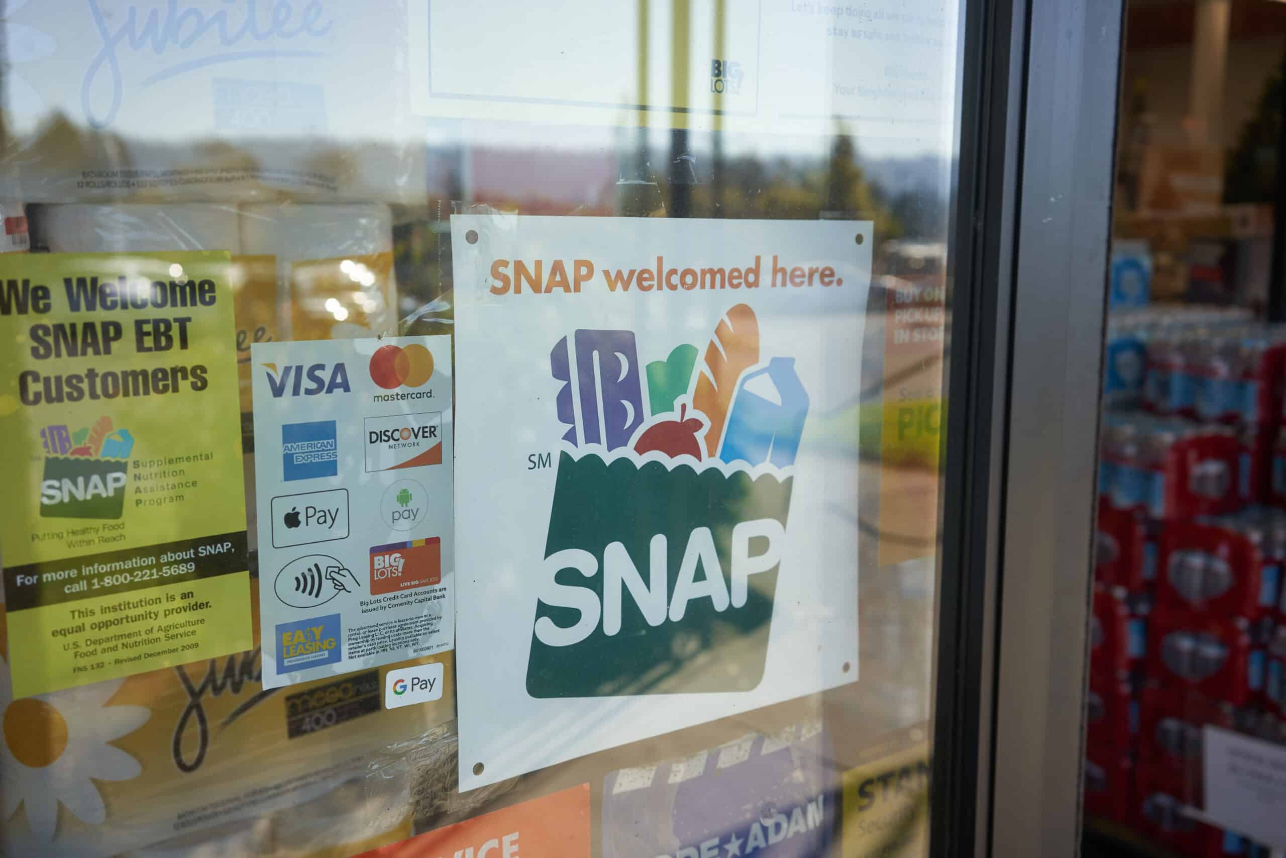 A storefront sign shows that SNAP EBT benefits are accepted at a local grocery and convenience store.