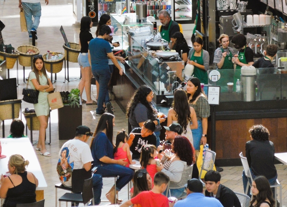 Customers ordering and sitting at a busy Starbucks café inside a shopping mall.