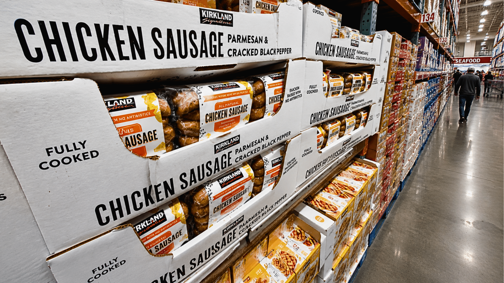 Kirkland Signature chicken sausage boxes stacked in a Costco warehouse aisle.