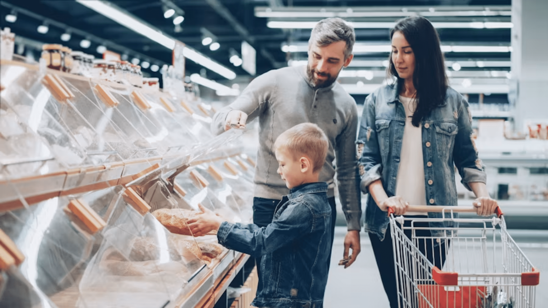 Family shopping for bread in a grocery store bakery aisle.