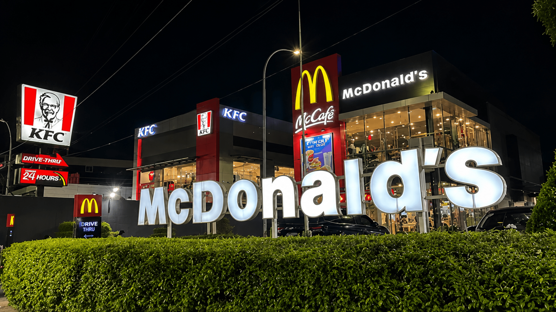 A McDonald's restaurant and a KFC restaurant illuminated next to each other at night.