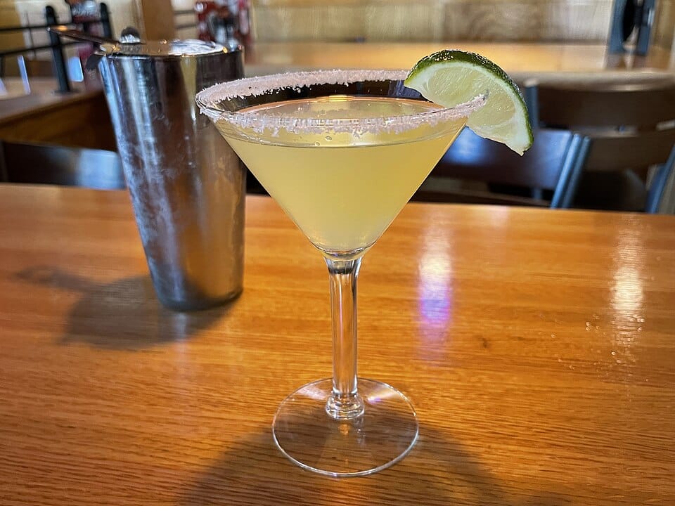 Classic margarita with a salted rim and lime wedge served in a cocktail glass.