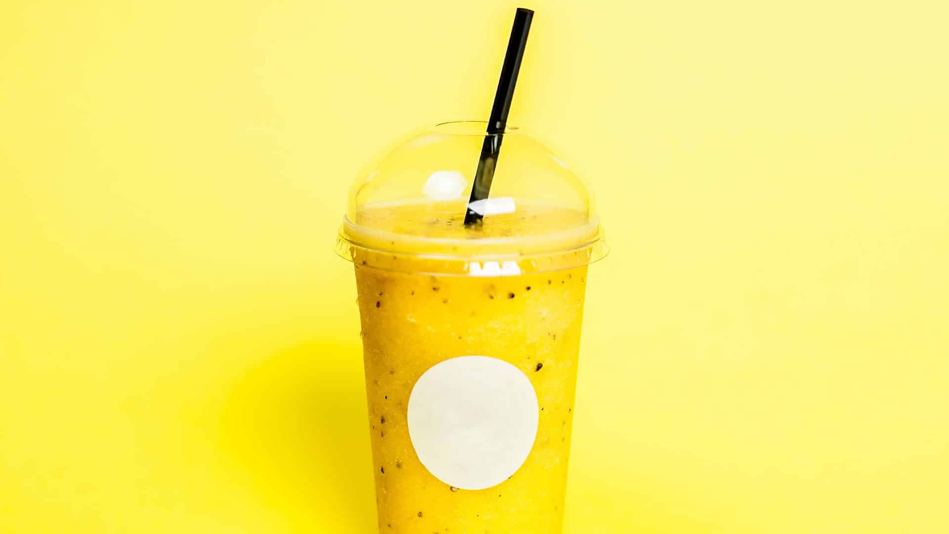 Yellow smothie plastic glass with juice.