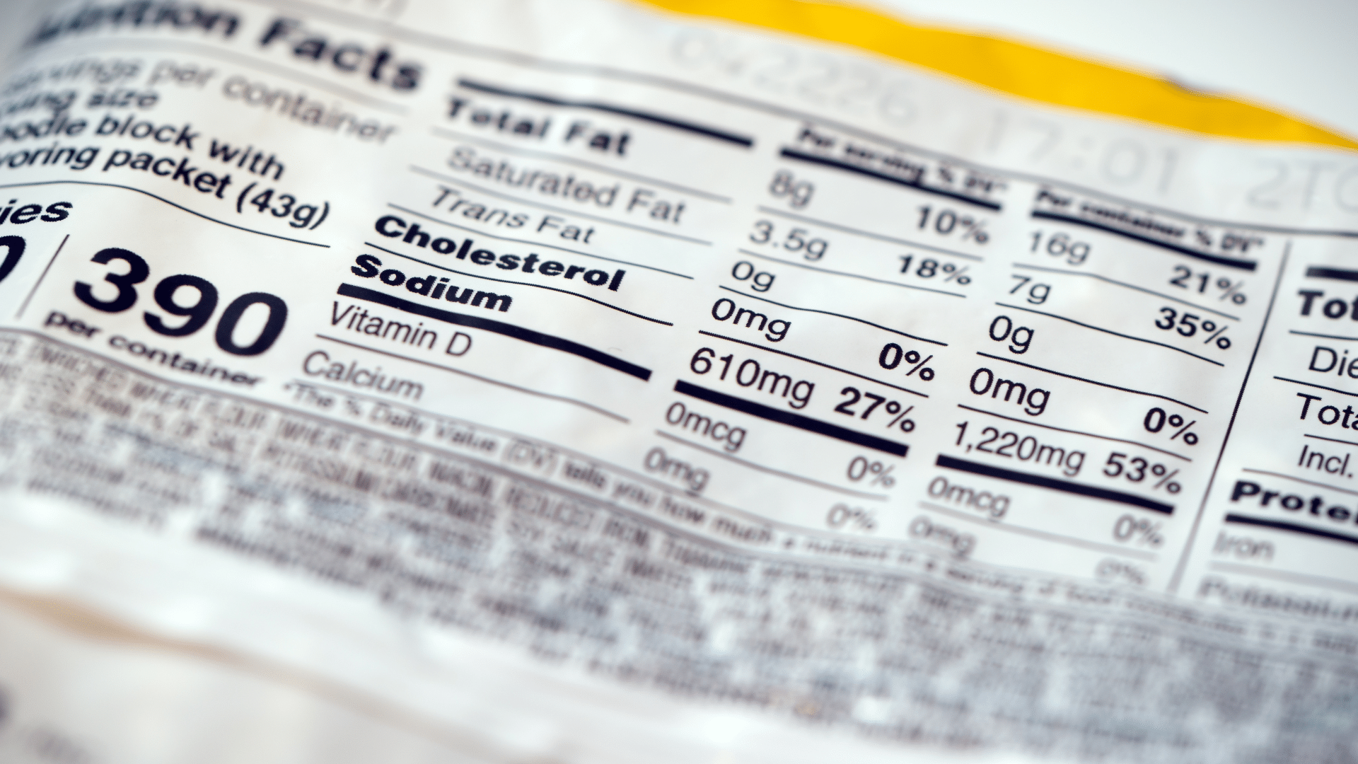 A close-up shot focuses on the detailed _Nutrition Facts_ panel printed on a plastic packaged food wrapper, highlighting the sodium and total fat content.