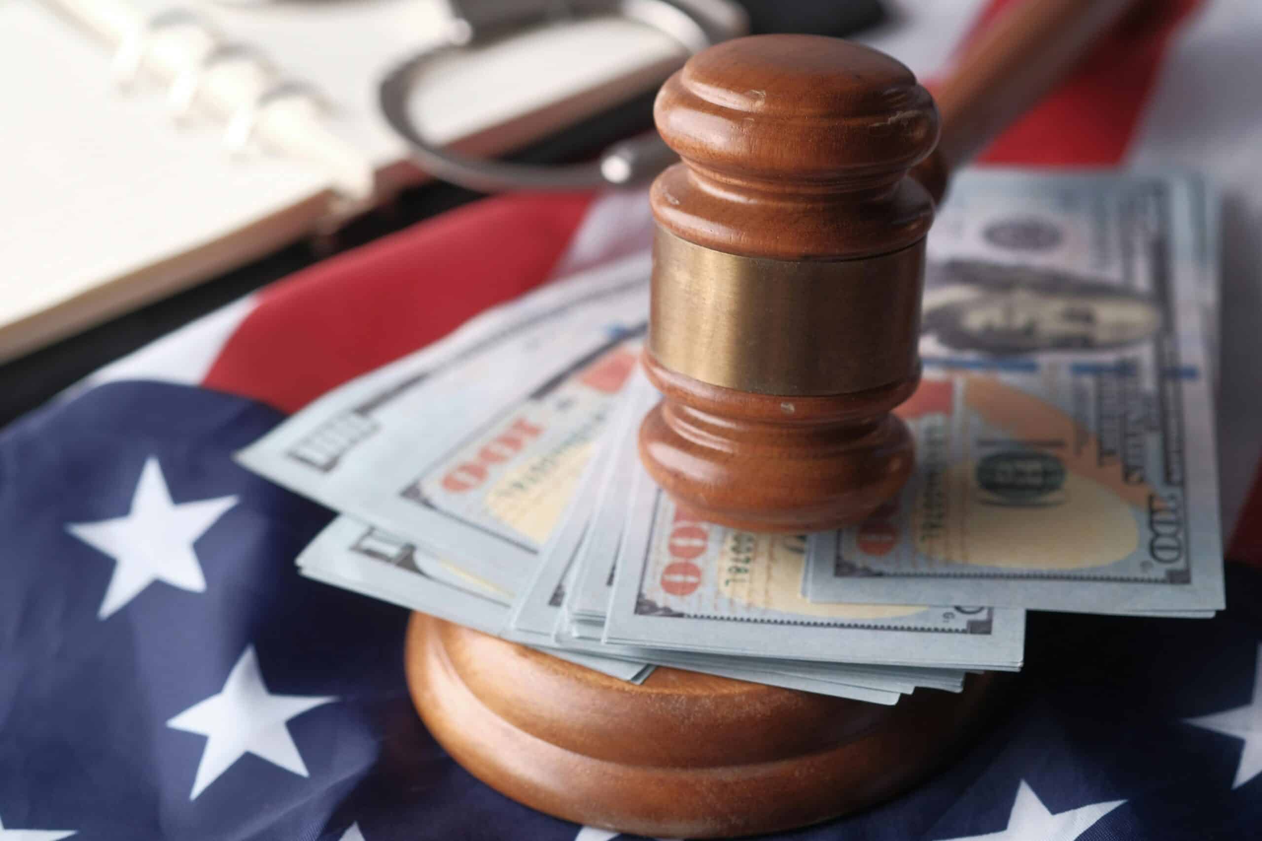 Judge’s gavel resting on U.S. currency and an American flag, representing legal disputes.