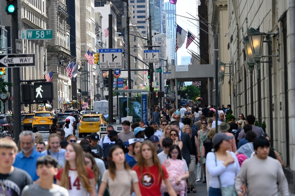 People walking along Fifth Avenue between West 57th Street and West 58th Street in New York City.