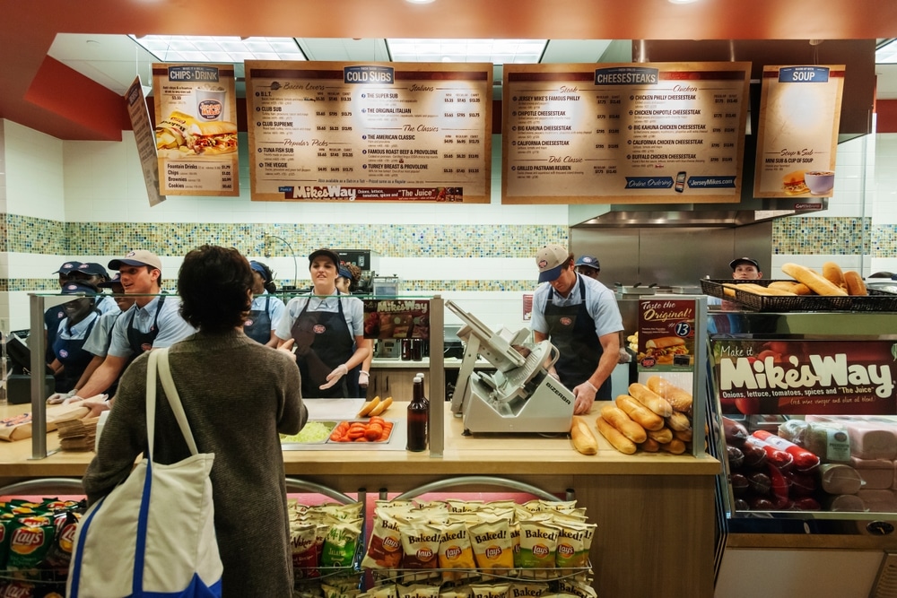 Employees prepare sandwiches behind the counter at a Jersey Mike’s Subs restaurant.