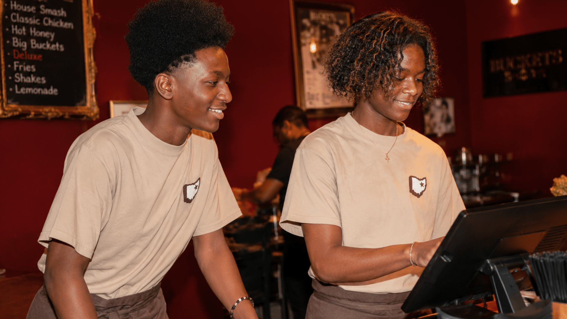 Twins Raelyn and Raymel work together using a point-of-sale monitor at Buckets restaurant inside House Three Thirty.