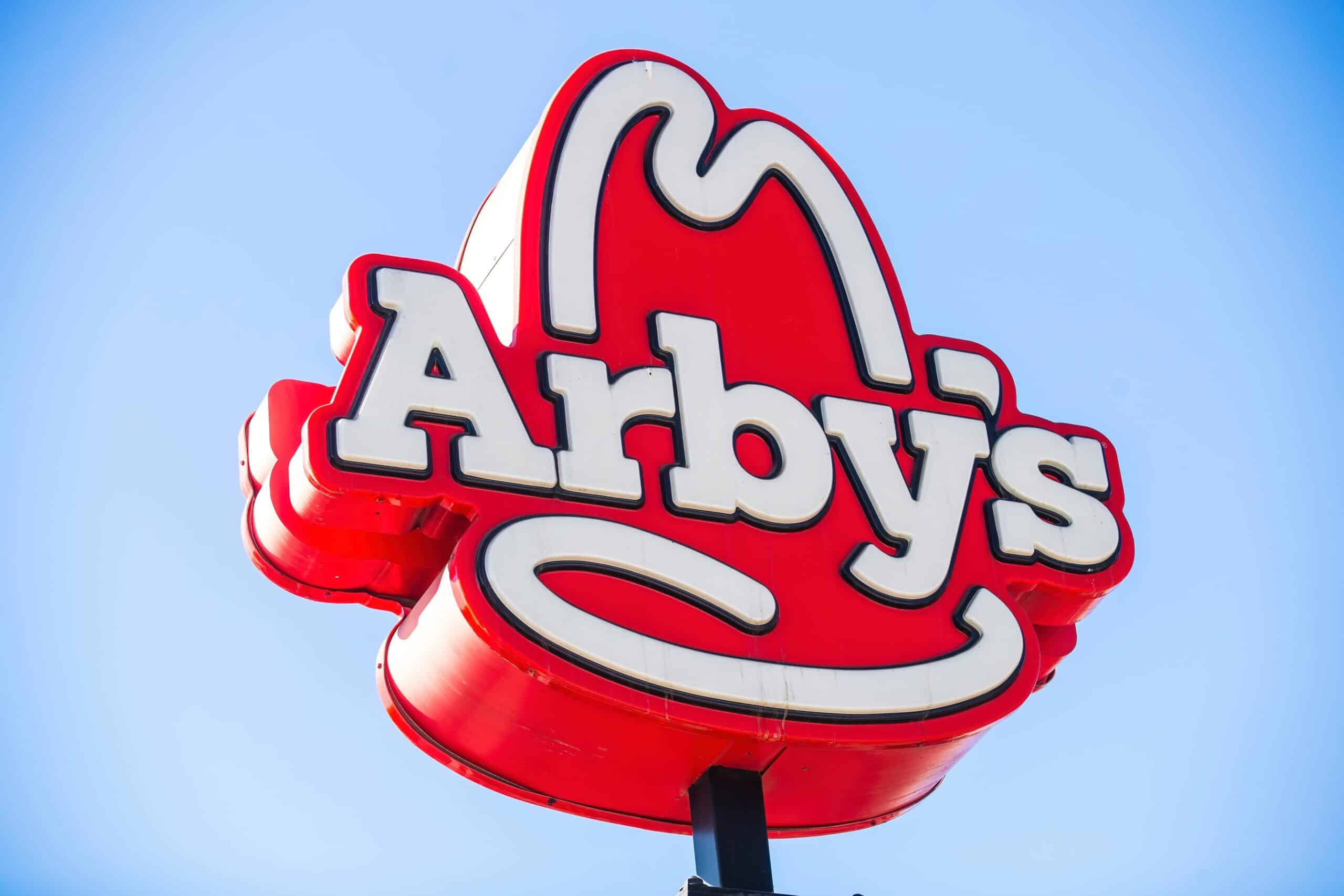 Close-up of a large Arby's restaurant sign against a clear blue sky.