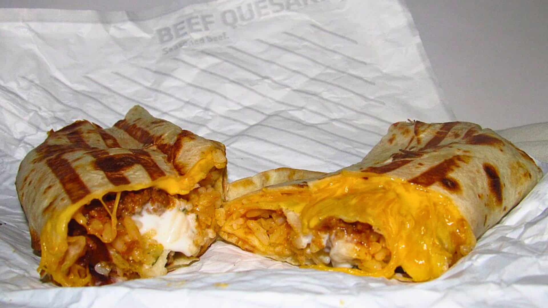 Cut-open Taco Bell Quesarito showing melted cheese, rice, meat, and sour cream.