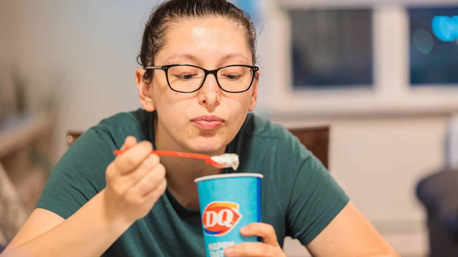 Woman eating a frozen dessert from a Dairy Queen cup with a spoon.