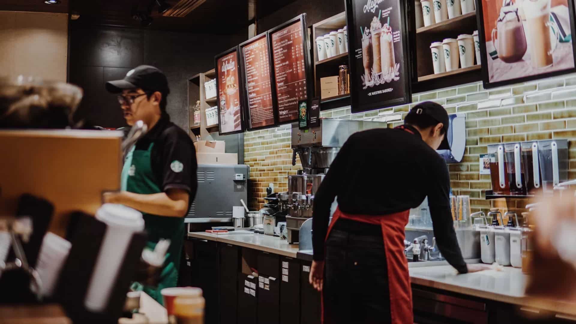 Starbucks baristas working behind the counter beneath menu boards.