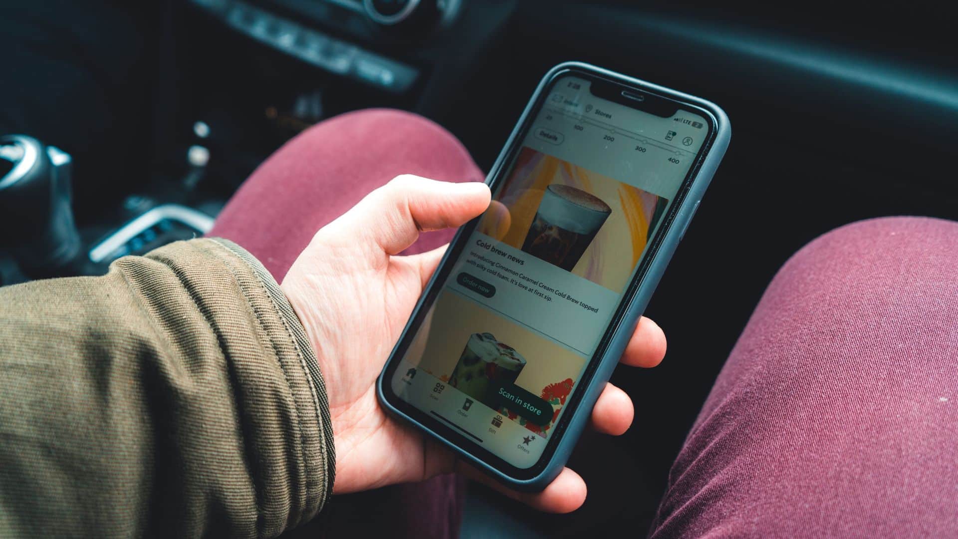 Person viewing the Starbucks app on a smartphone while sitting in a car.