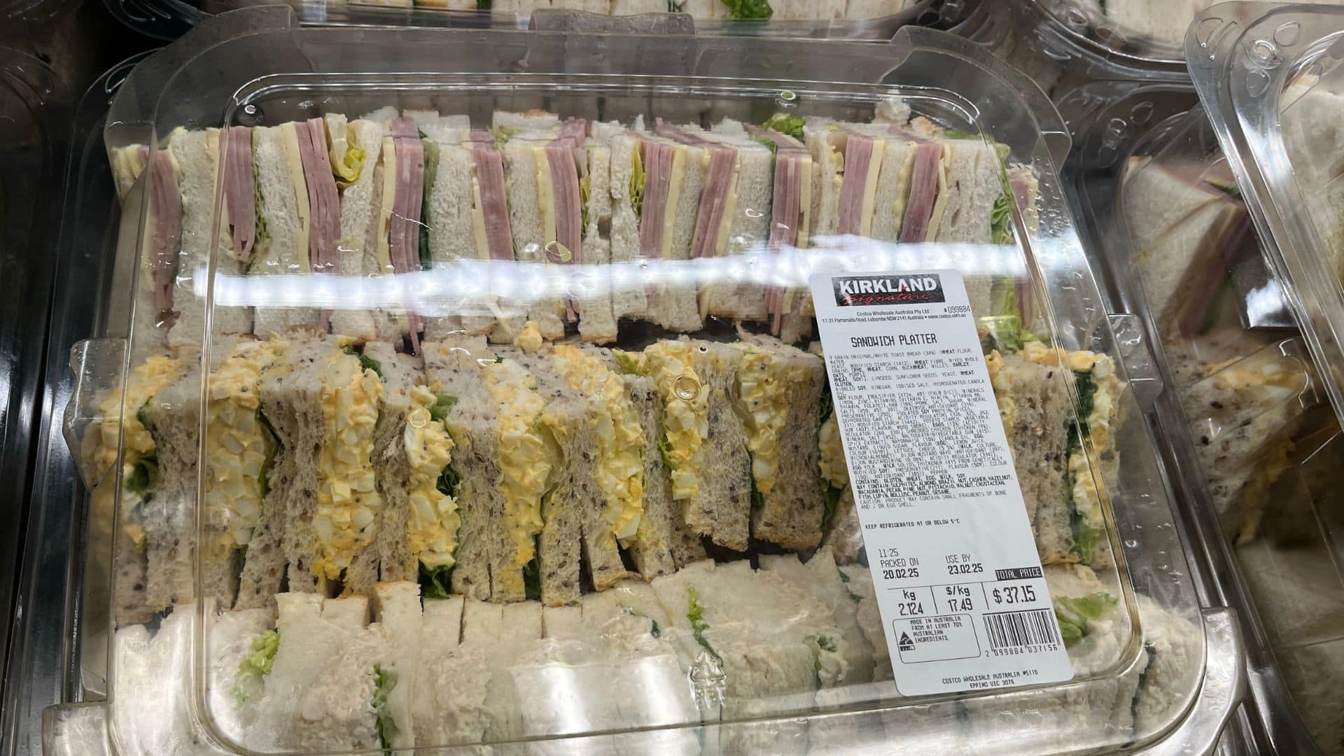 Kirkland Signature sandwich platter with assorted sandwiches in a clear container.