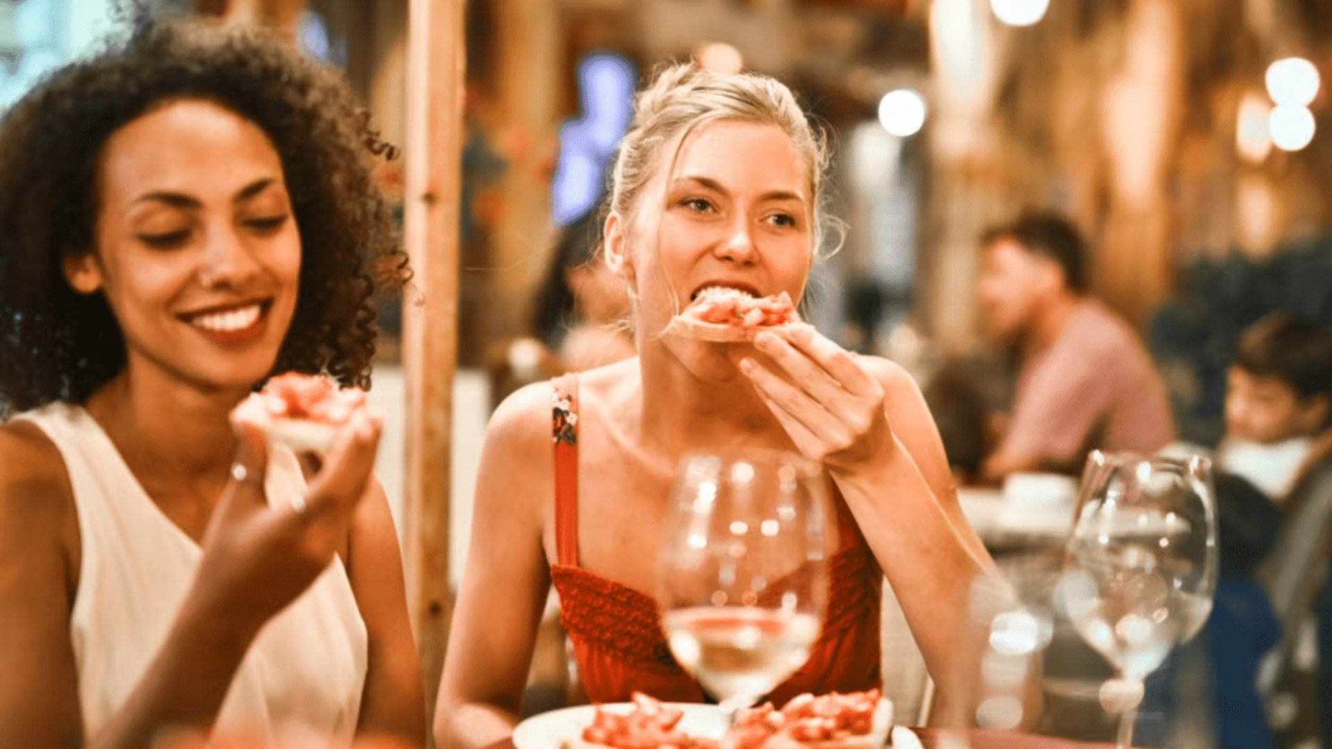 Two smiling women eating at a restaurant table.