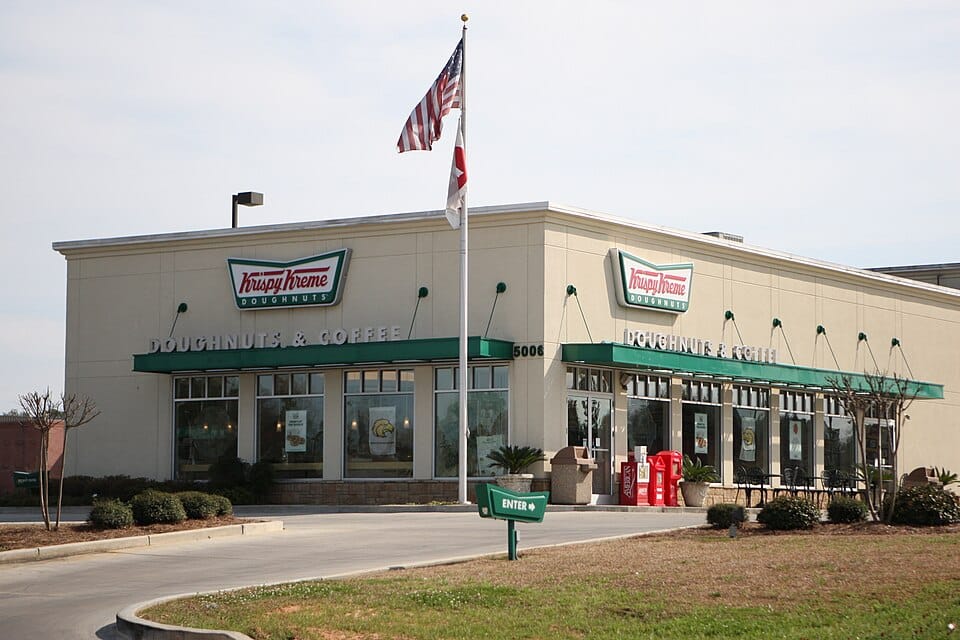Exterior of a Krispy Kreme doughnut and coffee shop with the company’s signs displayed above the entrance.