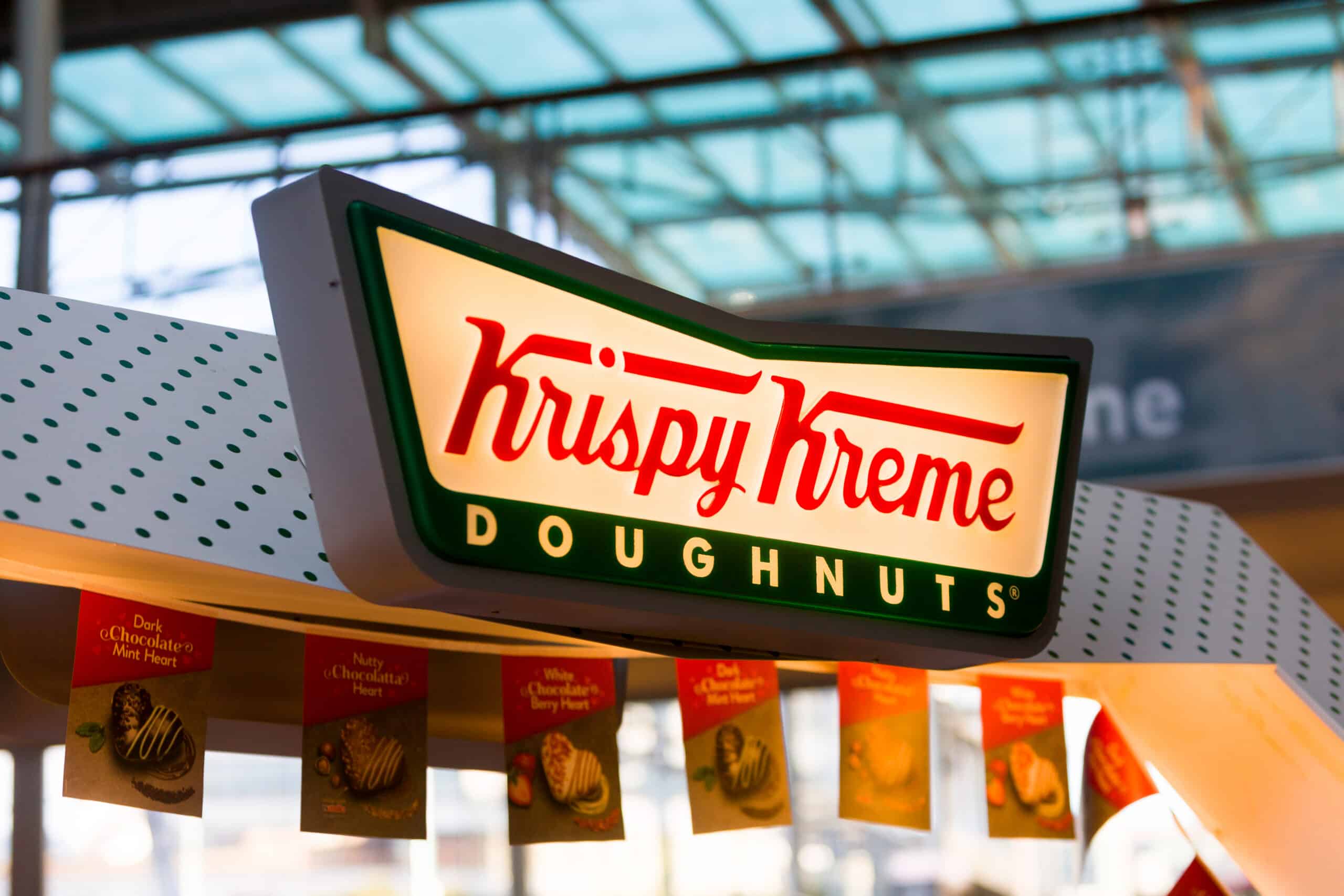 An illuminated Krispy Kreme Doughnuts sign displayed above a shop counter.