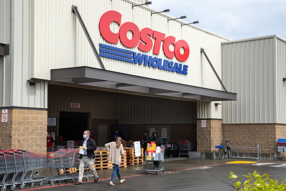 Costco Wholesale storefront with shoppers and shopping carts gathered near the entrance.