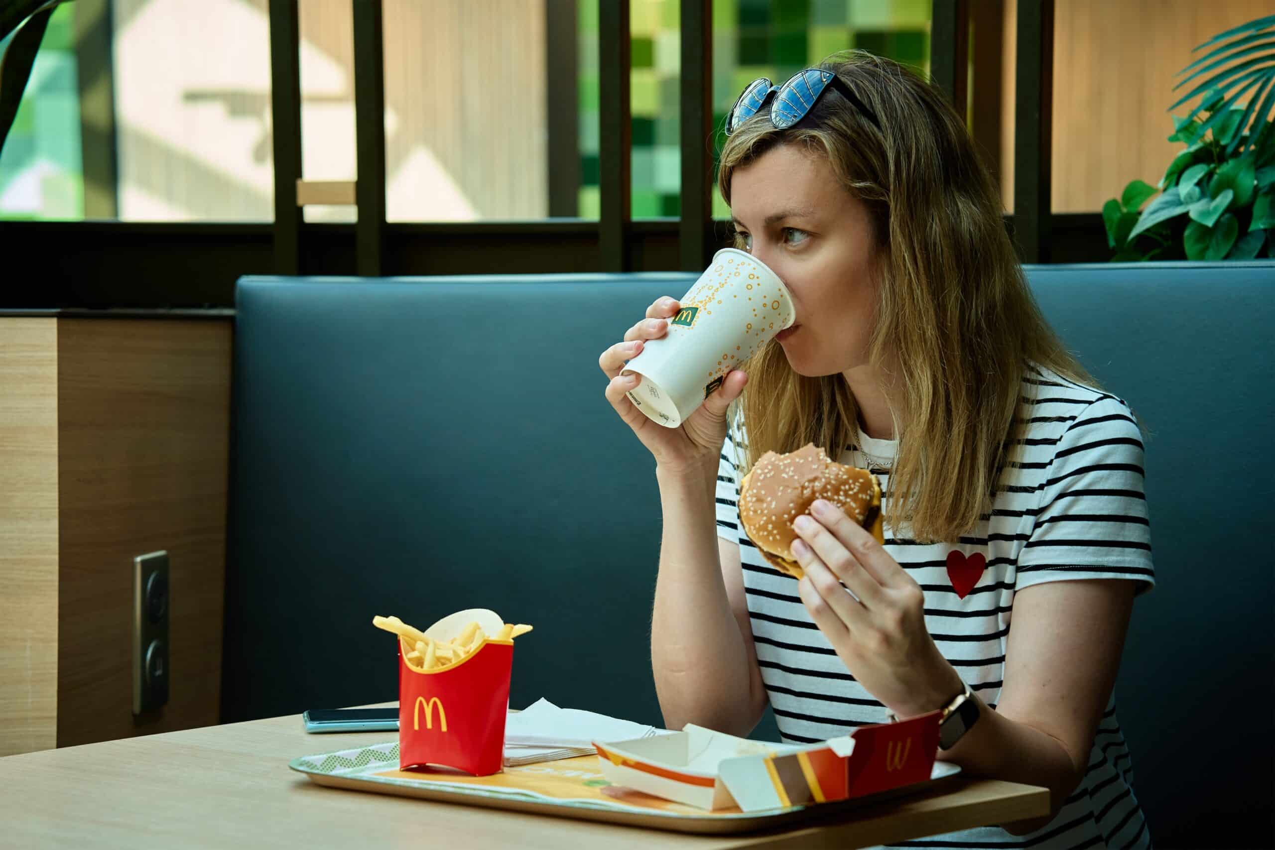 Customer enjoying a drink with a burger and fries at McDonald’s, where beverages are becoming a bigger part of the chain’s growth strategy.