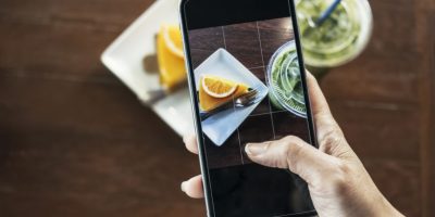 Smartphone take shot orange cake with orange topping and iced green tea photo