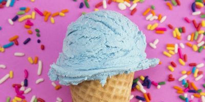 Delicious Pink Ice Cream with Sprinkles in a Waffle Cone on Blue